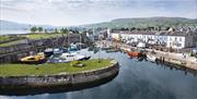 Aerial view of Carnlough Harbour with shops and homes in the background and boats in the harbour