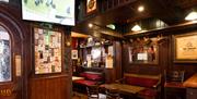 Front entrance to Charlie's Bar Enniskillen, where racing is being shown on a sports screen above the door, with a traditional Irish interior and old