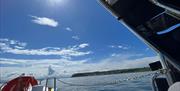 View of coastline with wake of sea behind boat and life ring visible on Charter NI Boat