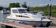 cruise boat in water tied up to wooden jetty