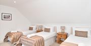 three single beds with 2 beside tables with lamps between the beds.