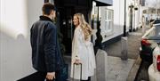 couple at front entrance of Hotel with suitcases