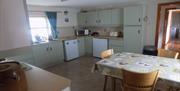 Image shows large kitchen with dining table and chairs