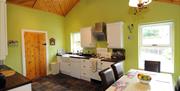 Image shows kitchen and dining area with tiled floor and table and chairs