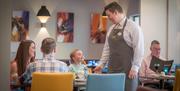 A family with a child being served by a waiter in the restaurant.