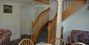 A sitting area with two chairs, a staircase leading upstairs and a pillar.