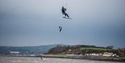 Kite surfers on the water and one in the air