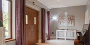 Modern tiled hallway with piano and good lighting and double entry doors