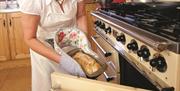 Woman taking home made bread out of the oven