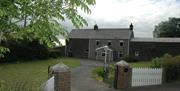 A driveway leading to a large grey farmhouse.