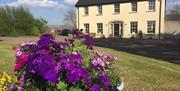 The exterior of the Rocks Bed and Breakfast, showing the garden and front of this traditional farm house.