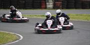 Three racers carefully turn a corner in their go-karts.