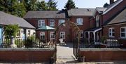 Image shows front of property with archway entrance and small courtyard with seating area