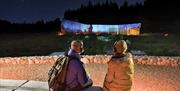 A couple with headphones watching the outdoor projection of the sky