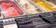 3 ice-creams displayed  in serving counter with sign reading honeycomb, chocolate and strawberry