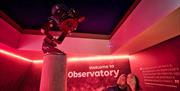 A couple looking up at a telescope at the OM Dark Sky Observatory