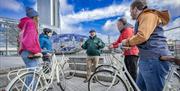 Steven from Hometown Tours stops beside the big fish with three tourists on bikes.