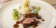 A plate of food in a restaurant with beef and potato