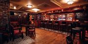 An image of a traditional bar area with bar stools and tables to sit at.