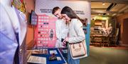 Couple look at a display at the Derry Girls Exhibition