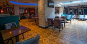 An image showing a restaurant floor area with tables and chairs and a stone pillar with a TV.