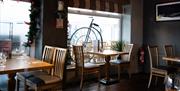 A restaurant with windows and tables set with wine glasses and cutlery.