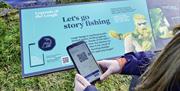 A girl with a smartphone scanning the interpretation boards at Ballyronan Marina.