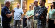 Group of visitors listening to tour guide inside US Rangers Museum.