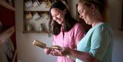 Two visitors holding items inside the Andrew Jackson Cottage