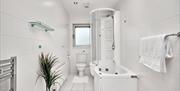 Photograph of bathroom with shower over the bath, the bath has jets.