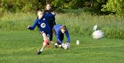 teenage boy kicking ball on footgolf course