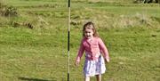 young girl kicking the ball into the flagged cup at Newtownabbey Footgolf