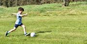 young boys kicks football at Newtownabbey footgolf