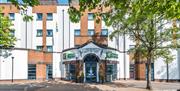 Photo of the exterior of the Holiday Inn Express Belfast City, Holiday Inn Express sign on the façade and trees on the sidewalk.