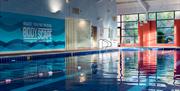 Photo of the swimming pool inside the Crowne Plaza Belfast hotel. Swimming lanes in the foreground, bubble spa, sauna and steam room in the background