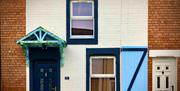 A painted terrace house designed with a light blue window shutter and canopy.