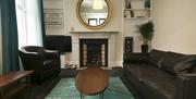 A carpeted living room with a coffee table, sofa, chair, TV and a fireplace.
