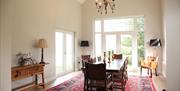 Image shows large dining room with table and 8 chairs. Patio doors onto garden area