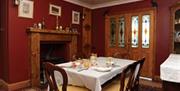 Dining room with a fireplace, table and chairs and double doors.