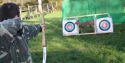 A man ready to fire an arrow at an archery target.