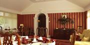 Dining room with a set table, flowers and a doorway.