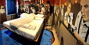 A photo of a Titanic-themed bedroom with murals of passengers on the ship, surrounding a double bed.