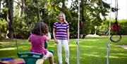 Image shows lady watching girl on swing in garden