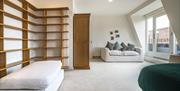 A large bedroom with a footrest next to a lot of shelves and a wardrobe.