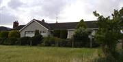 Image shows back of property overlooking field with trees and hedges