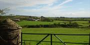 View over a black iron gate of hills and fields