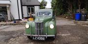 Driving an old Ford Prefect on the driveway.