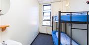 A photo of a room with one bunk bed and a sink with a mirror.