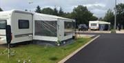 Caravans with awnings in the park with a gnome on the lawn.