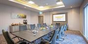 A conference room with a long meeting table, extra-large TV and refreshments.